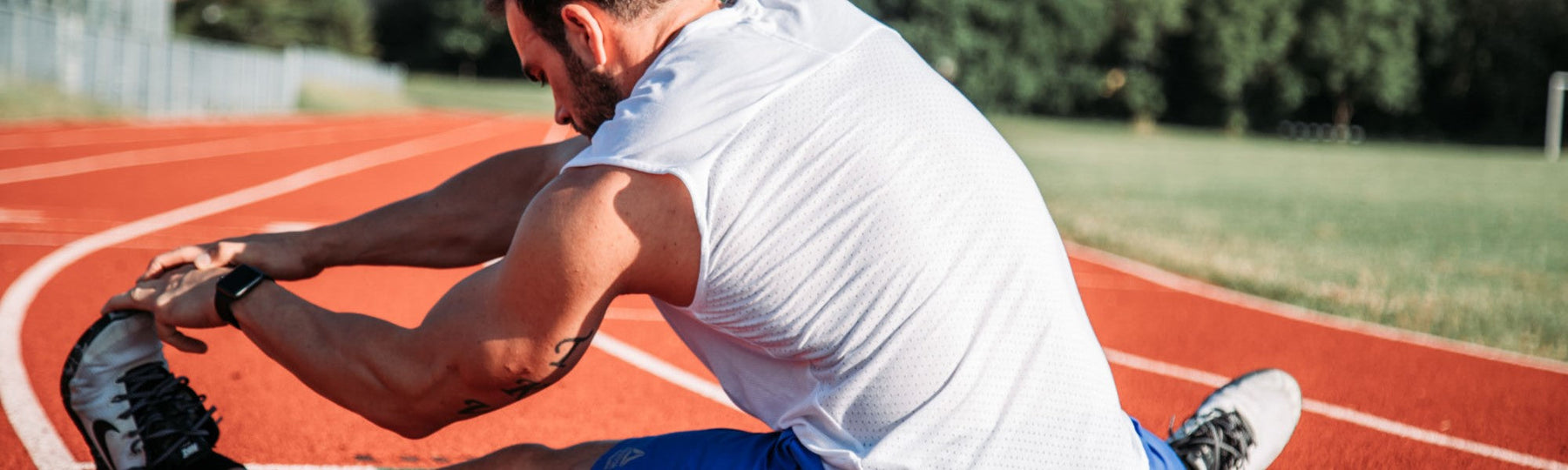 Male stretching legs on race track
