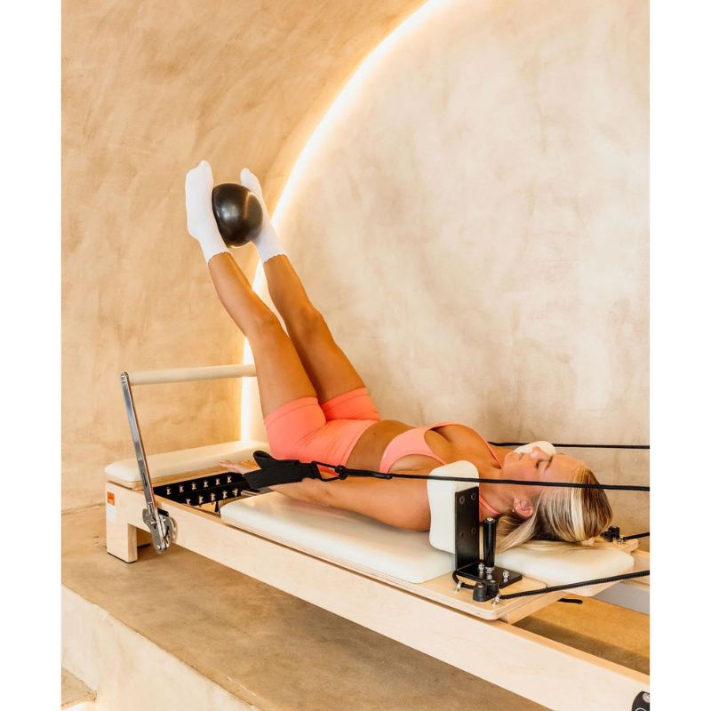 AussiePilatesCoastAP-01HomeReformerInCreamColourandFemaleUsingItwithsoftballbetweenfeet
