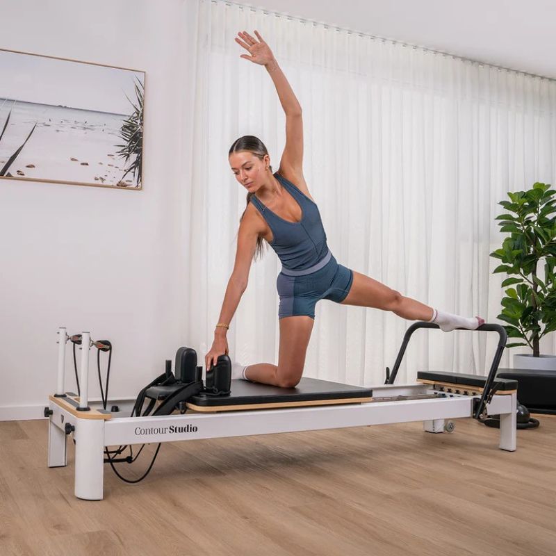 Contour Studio Commercial Pilates Reformer Machine in Black Colour with Woman Using It 