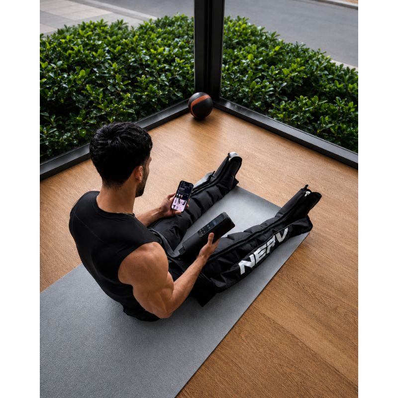NERV Squeeze Compression Boots with man sitting and using it while using a phone